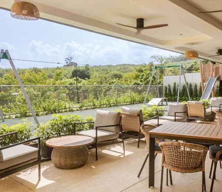 Open-air terrace lounge overlooking the playground and tropical greenery