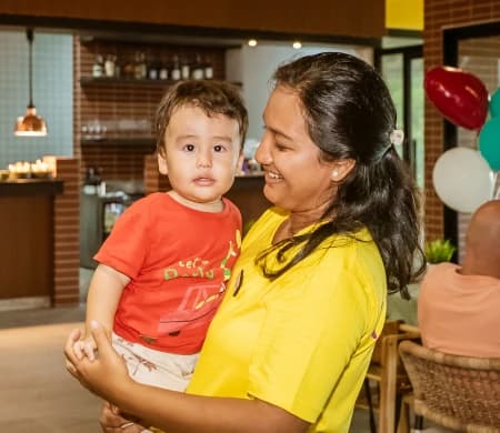 Mother holding her toddler at a birthday party with balloons