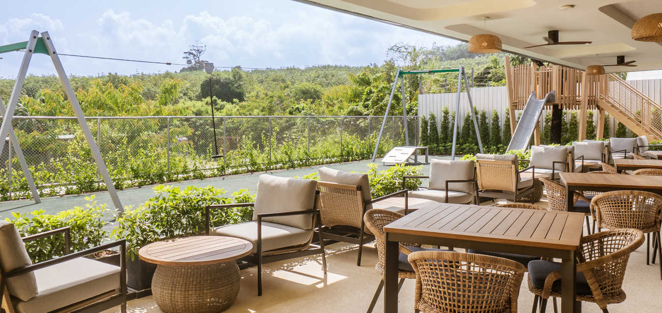 Shaded terrace seating overlooking the outdoor playground and greenery